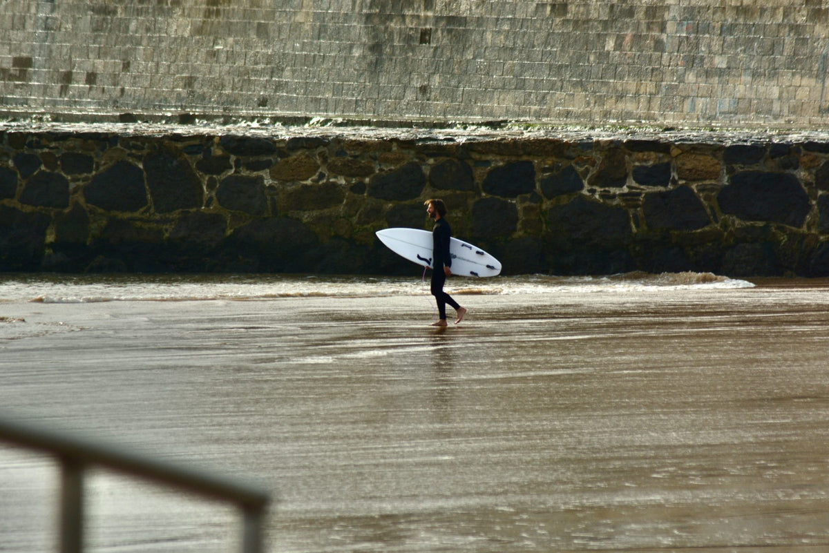 Surfer entering the water wearing SEAR Plugs