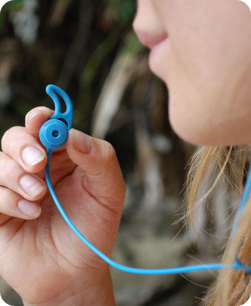 Close-up of a hand holding a blue reusable earplug with leash.