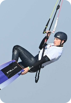 Kitesurfer jumping above the water while holding the control bar.