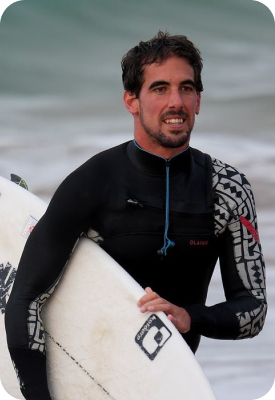 Man in a wetsuit holding a surfboard after a surf session.