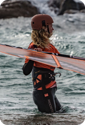 Windsurfer carrying a board while standing in shallow water.