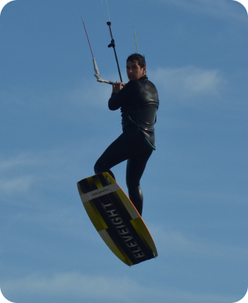Kitesurfer jumping high above the water while holding the control bar.