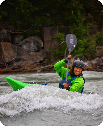 Kayaker navigating fast-moving river rapids between rocks.