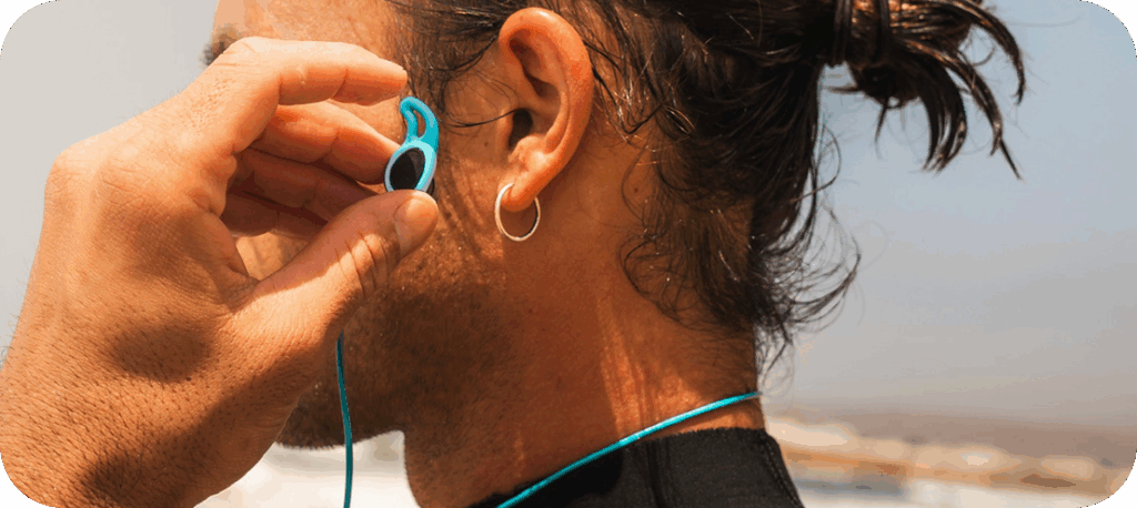 Close-up of an ear of a man wearing a blue water-sports earplug with safety leash.